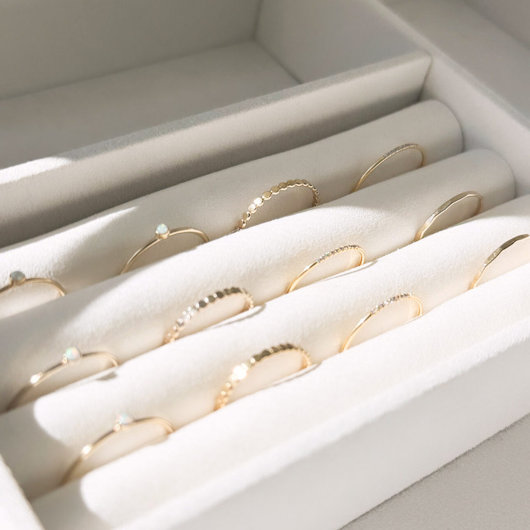 stackable gold rings laying in a beige velvet jewelry display
