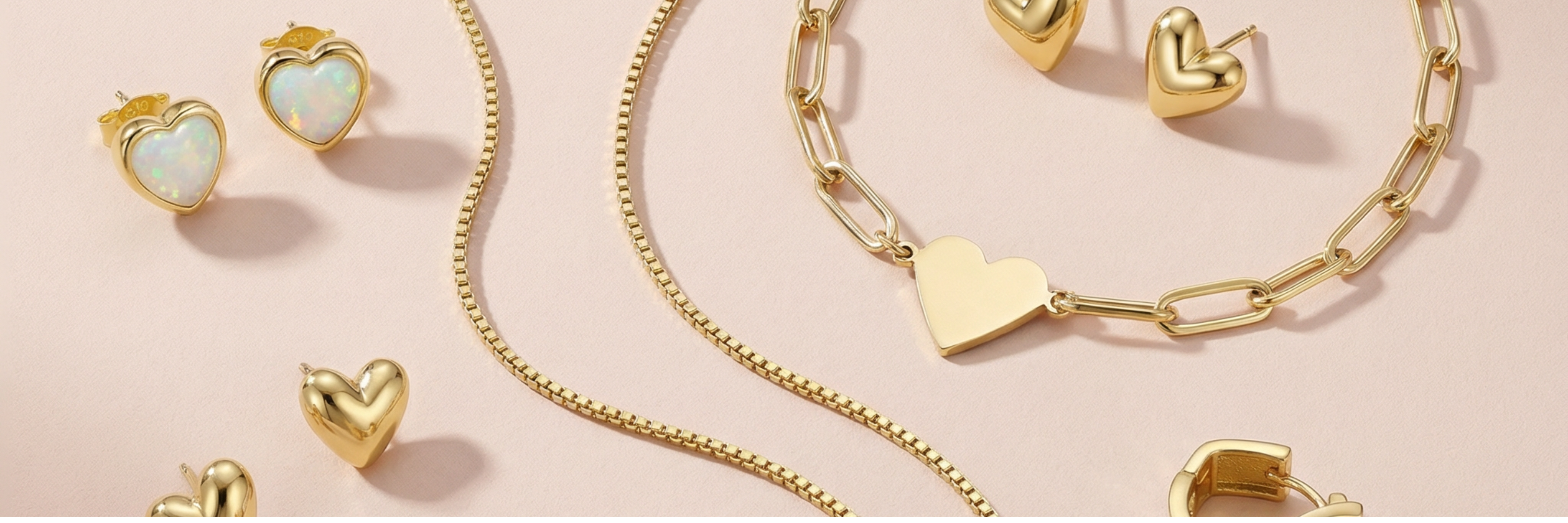 heart jewelry scattered on a light pink background