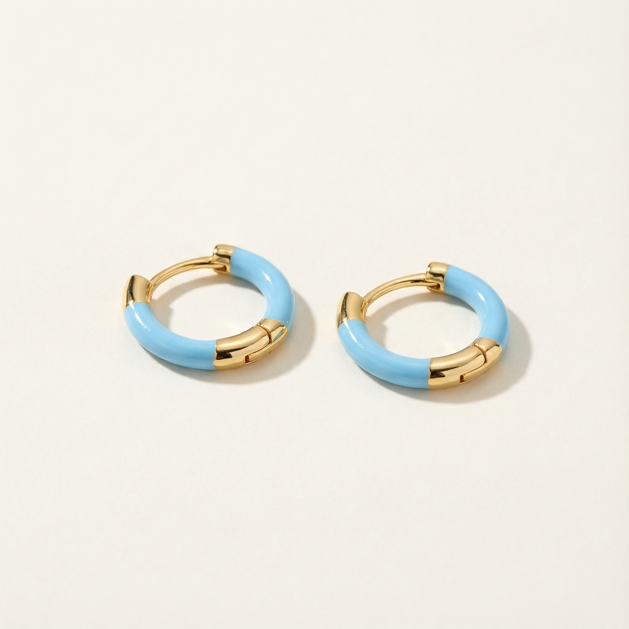 Pair of gold and light blue hoop earrings on a white background