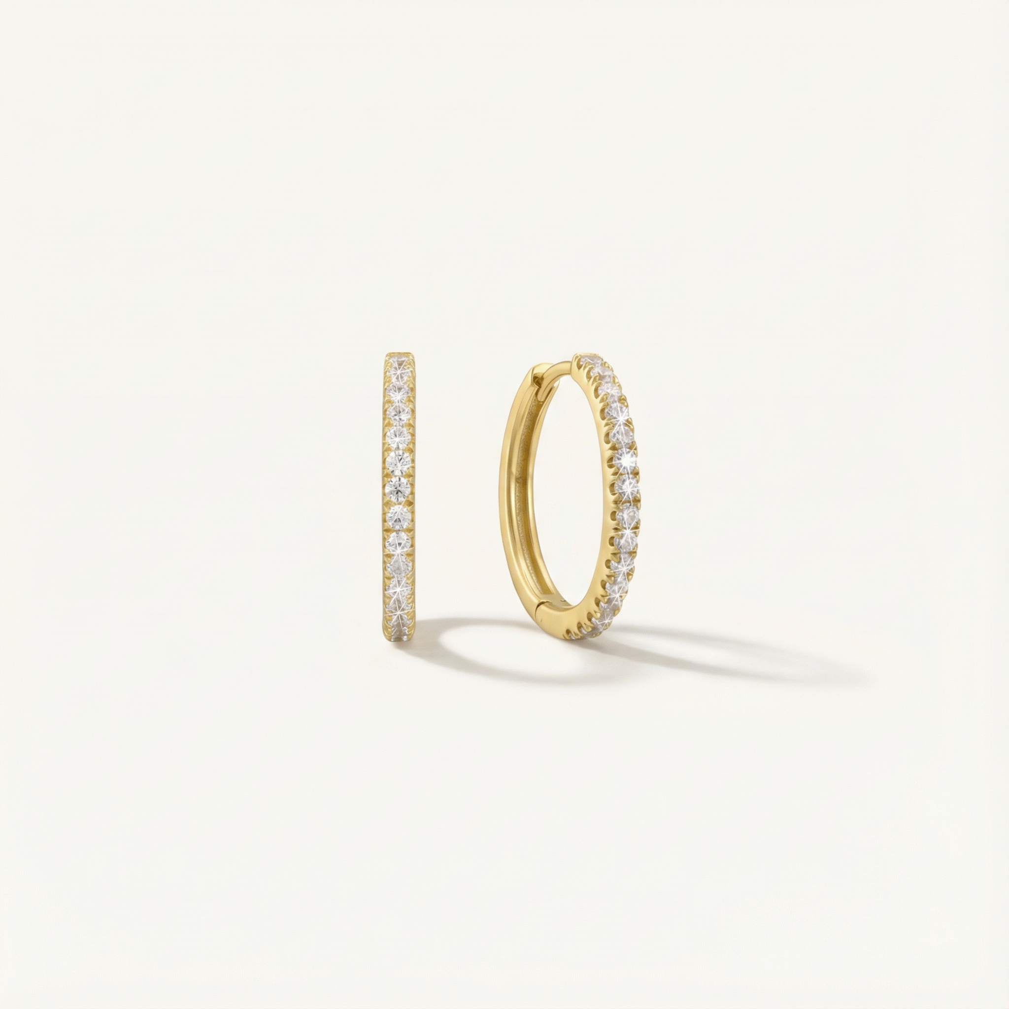 Gold hoop earrings with embedded diamonds on a light gray background