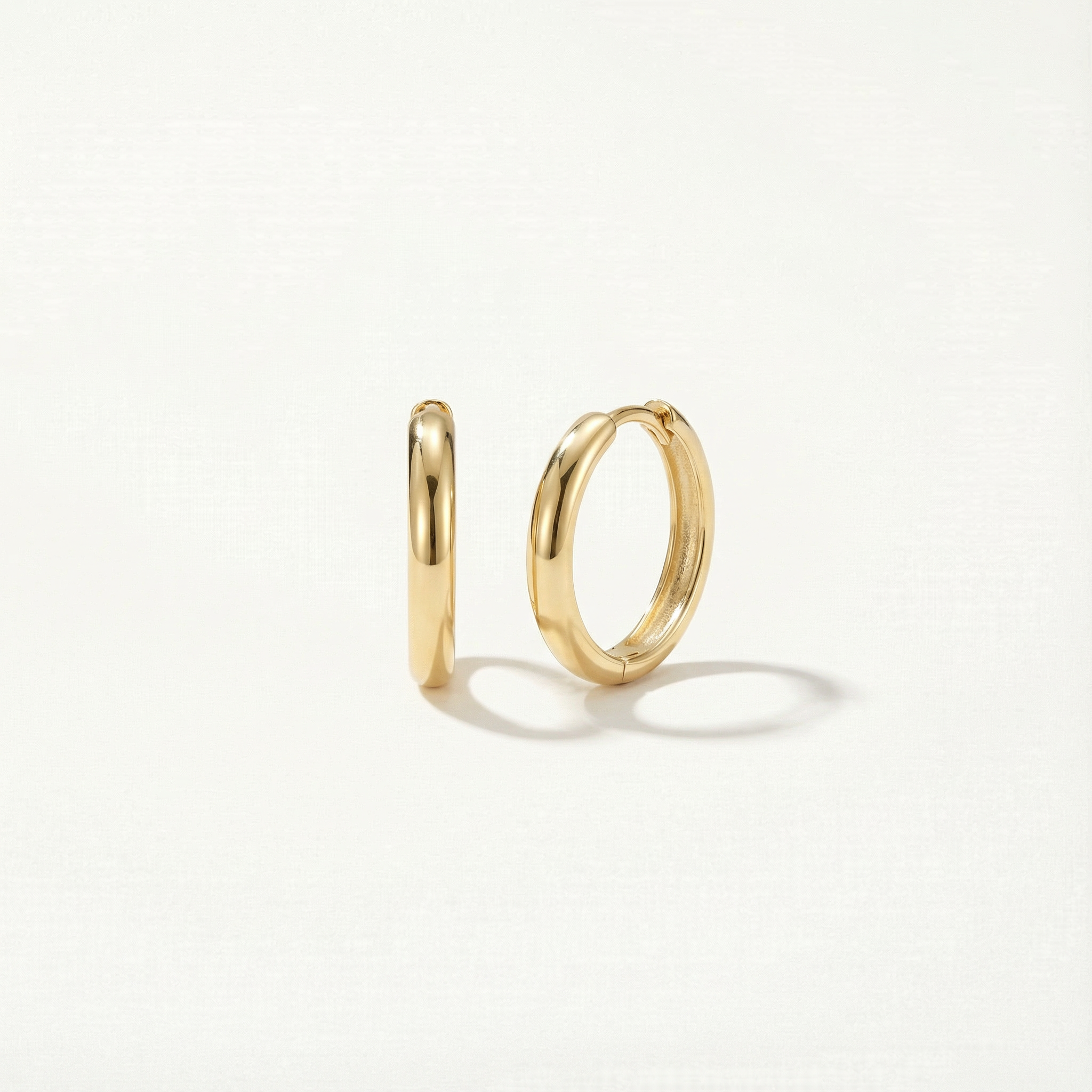 Two gold hoop earrings on a light gray background