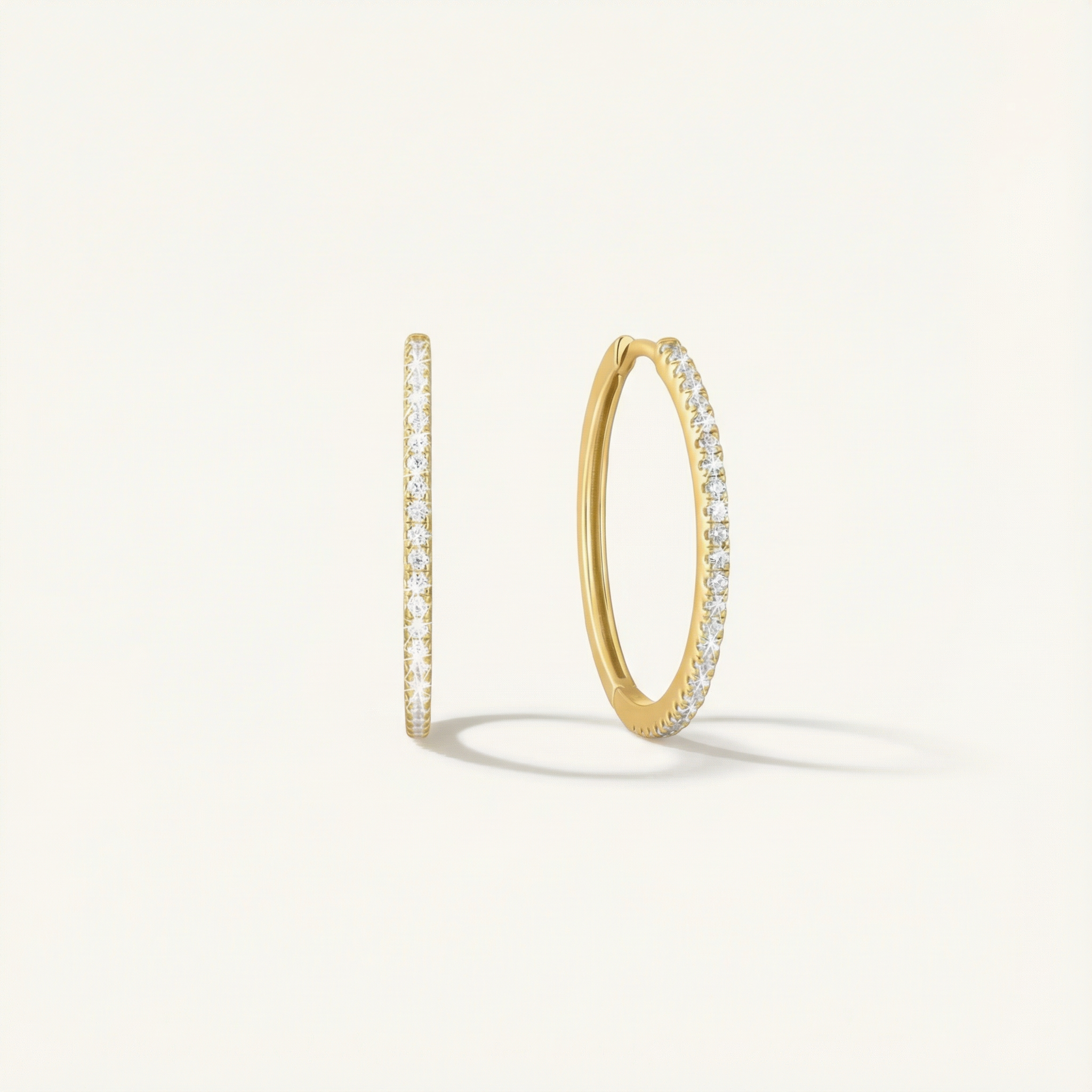 Gold hoop earrings with embedded diamonds on a light gray background