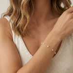 Close-up of a woman wearing a pearl bracelet on a neutral background