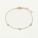 Gold bracelet with opal stones on a light beige background