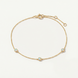 Gold bracelet with opal stones on a light beige background