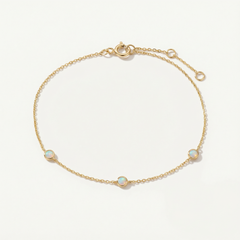 Gold bracelet with opal stones on a light beige background