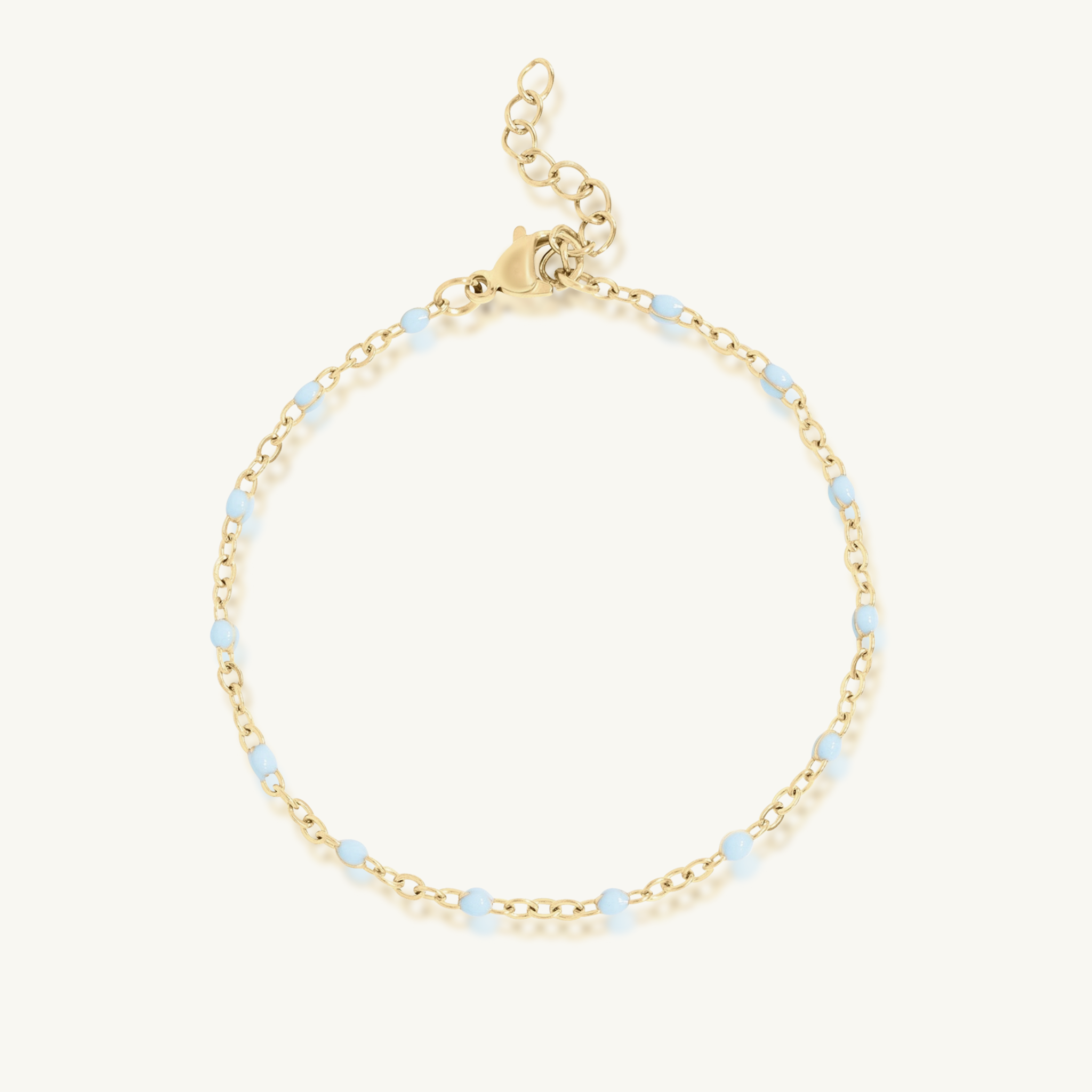 Gold bracelet with small blue beads on a white background