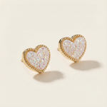 Heart-shaped earrings with gold rim and iridescent center on a beige background