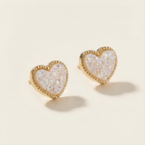 Heart-shaped earrings with gold rim and iridescent center on a beige background