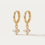 Gold hoop earrings with opal flower drops on a light beige background