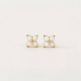Pair of gold and opal stud earrings on a light beige background