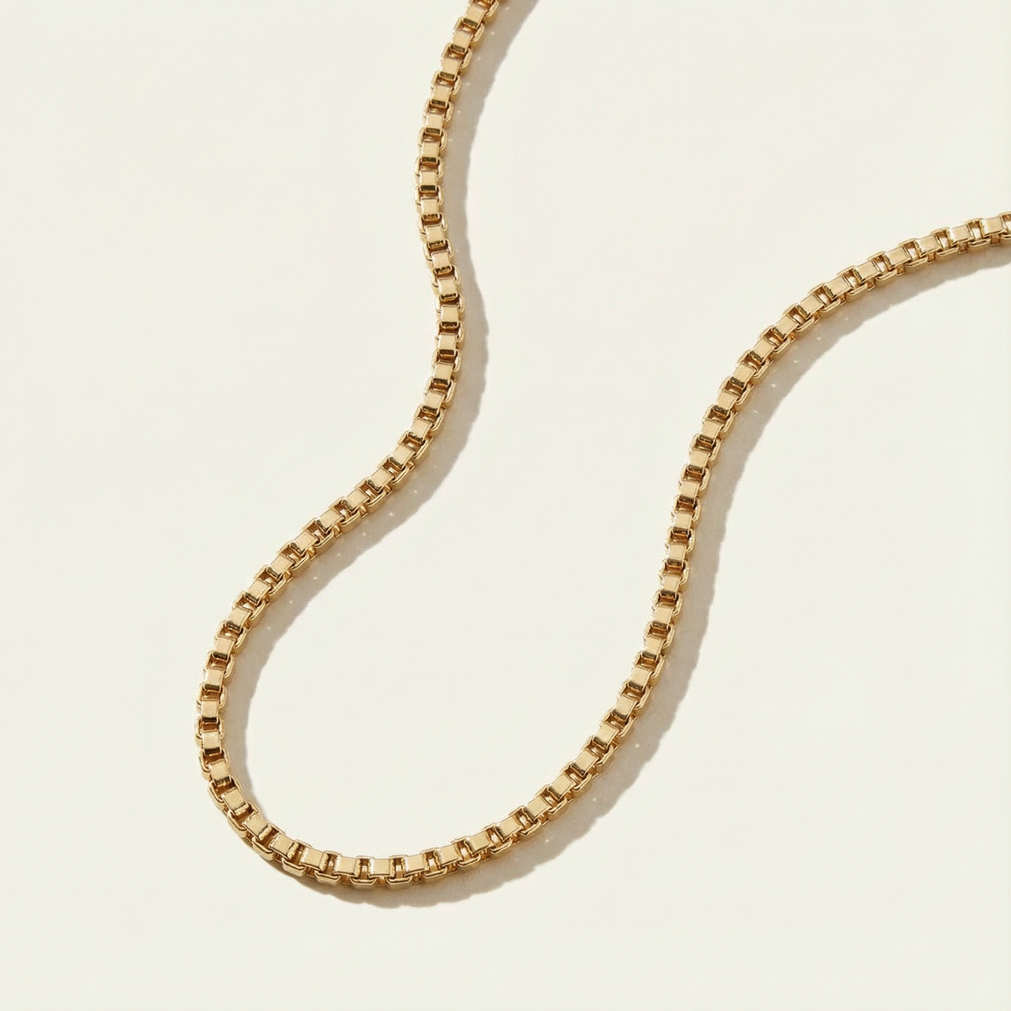 Gold Box Chain Necklace laying on a neutral background