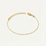 Gold dainty bracelet on a light beige background