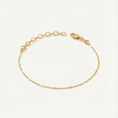 Gold dainty bracelet on a light beige background