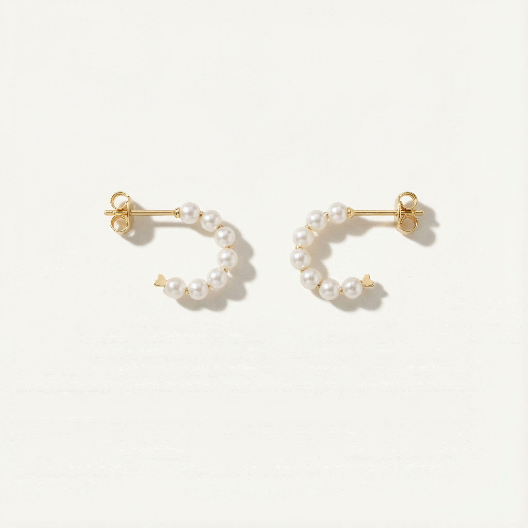 Pair of gold hoop earrings with pearl beads on a white background