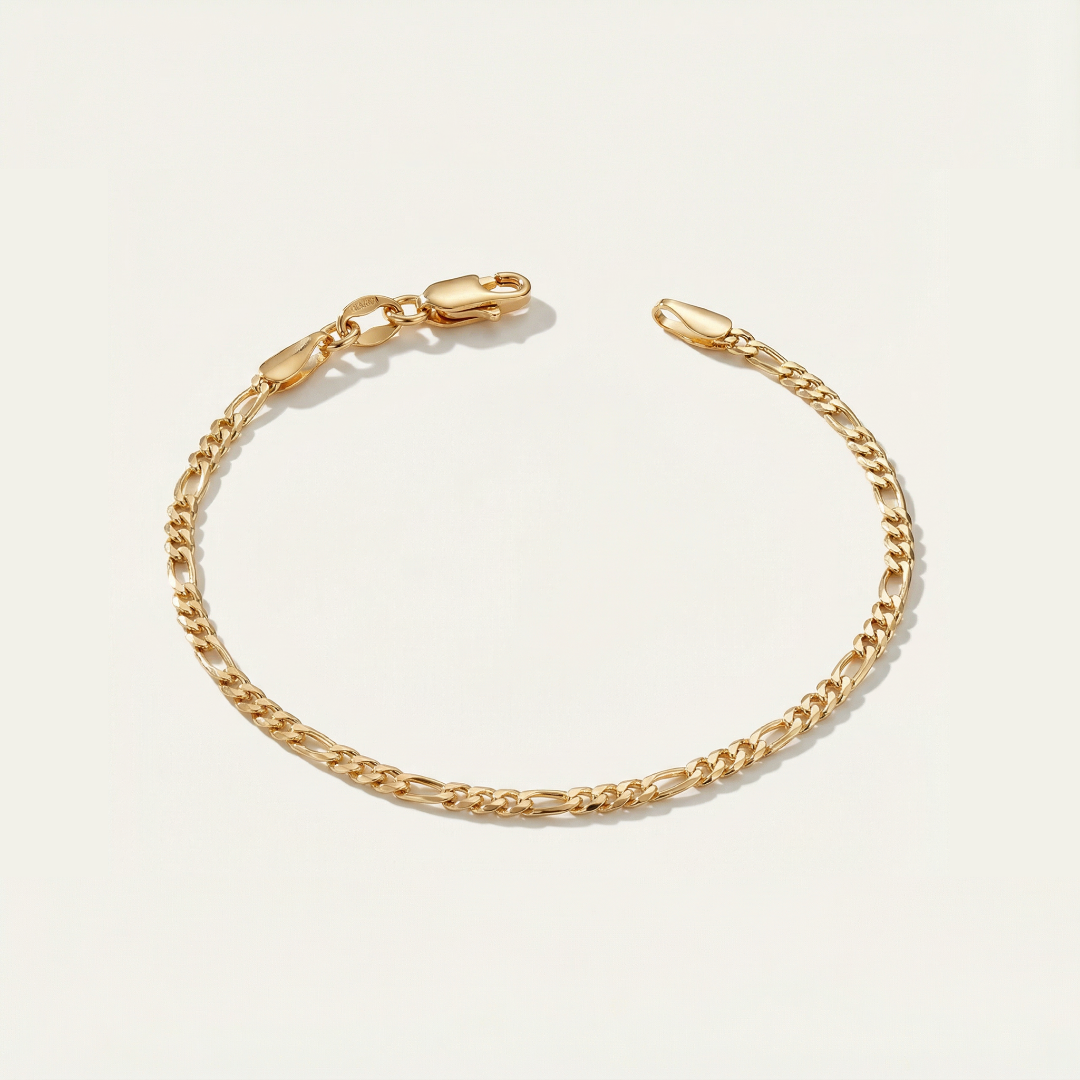 Gold figaro bracelet on a light beige background