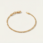 Gold figaro bracelet on a light beige background