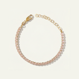 Bracelet with pink gemstones and gold chain on a light beige background