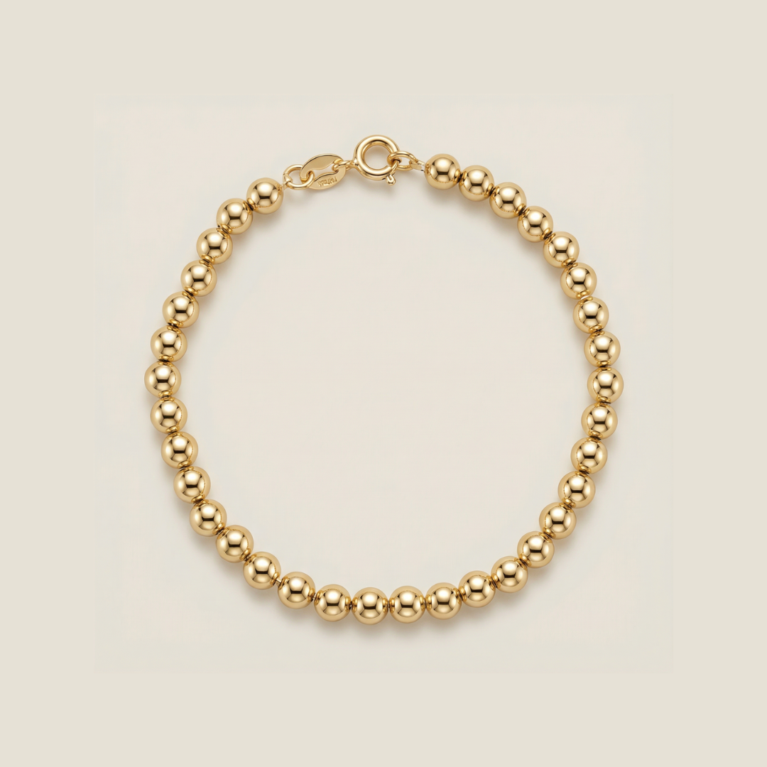 Gold beaded bracelet on a beige background