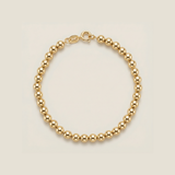 Gold beaded bracelet on a beige background