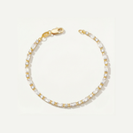 Gold tennis bracelet with cubic zirconia stones on a light gray background