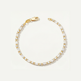 Gold tennis bracelet with cubic zirconia stones on a light gray background