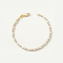 Gold tennis bracelet with cubic zirconia stones on a light gray background