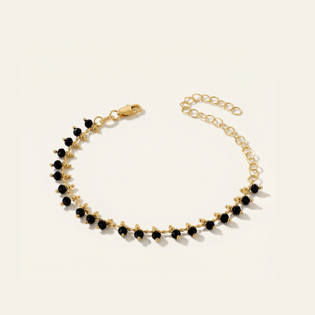 Gold bracelet with black beads on a light beige background