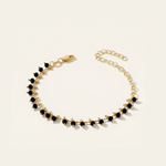 Gold bracelet with black beads on a light beige background