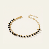 Gold bracelet with black beads on a light beige background