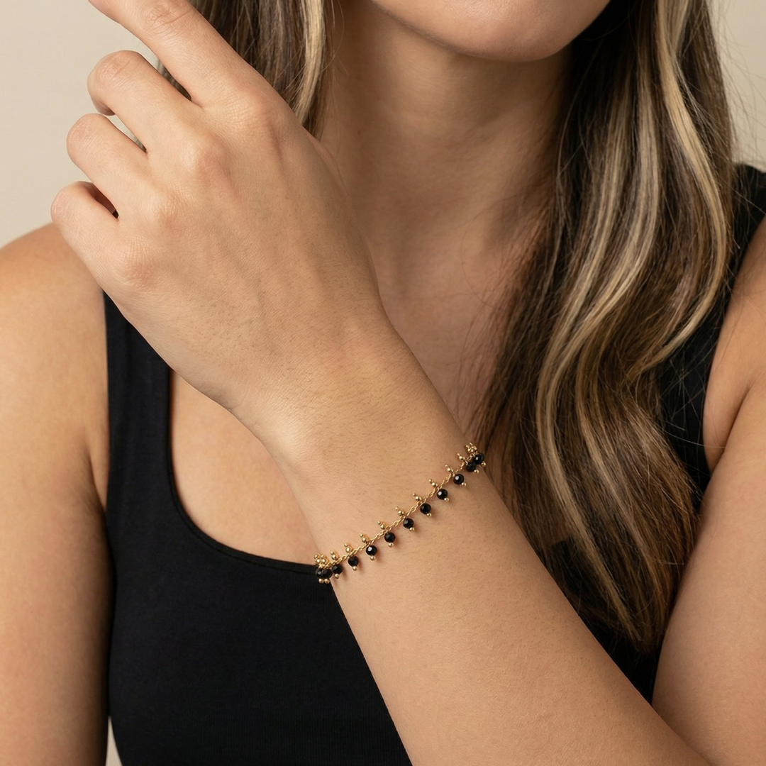 Woman wearing a black beaded bracelet on her wrist with a neutral background