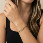 Woman wearing a black beaded bracelet on her wrist with a neutral background