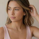Woman wearing a gold necklace against a neutral background