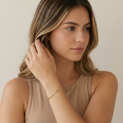 a women wearing a gold figaro chain bracelet