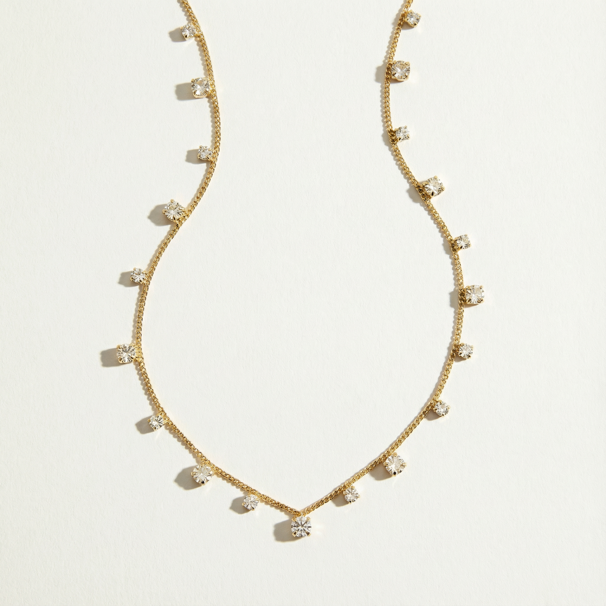Gold necklace with small diamonds on a light gray background