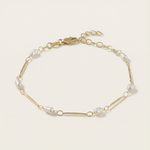 Gold bracelet with pearls on a light beige background