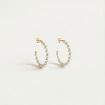 Pair of pearl hoop earrings on a light beige background