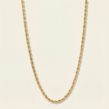 Gold rope chain necklace on a beige background