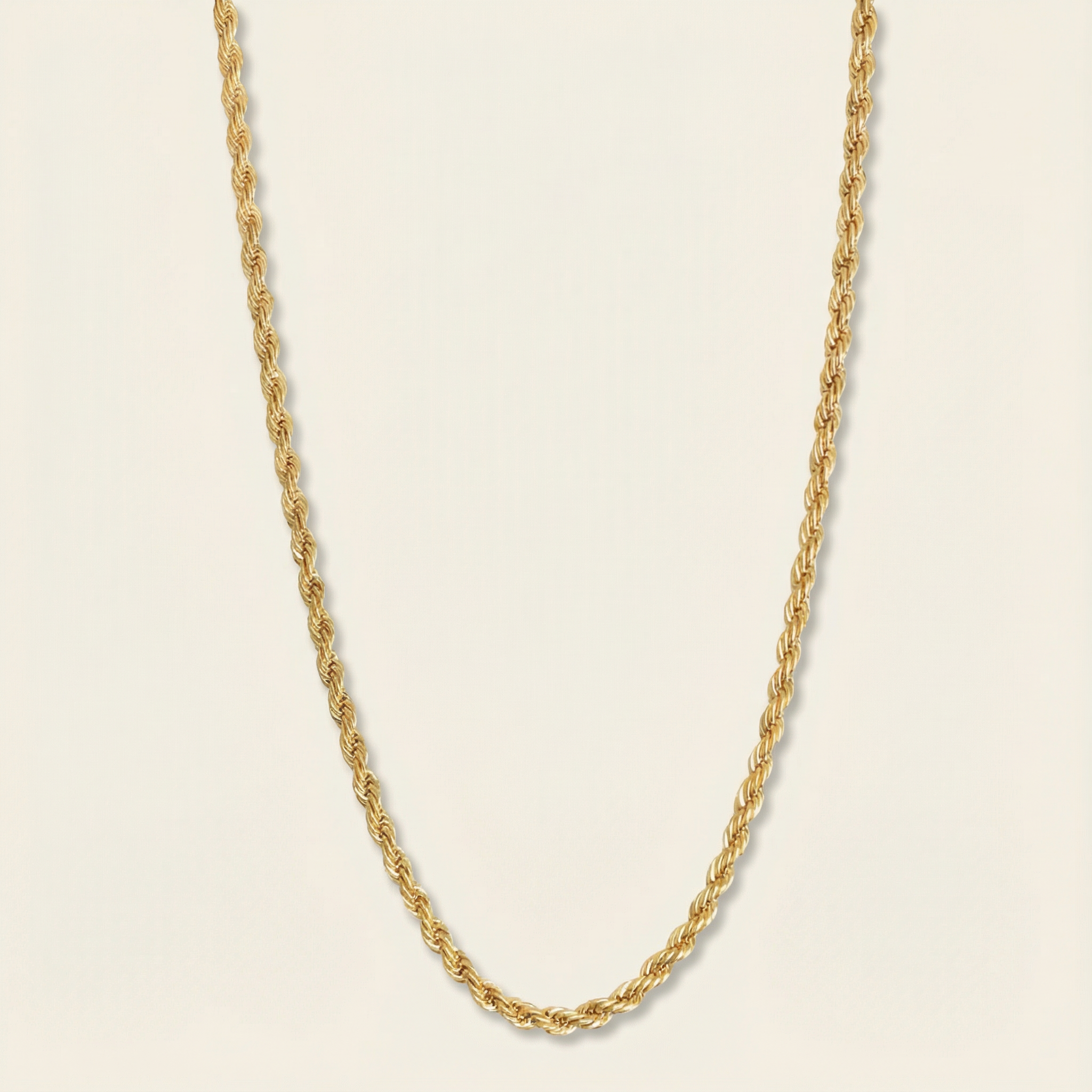 Gold rope chain necklace on a beige background
