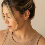 Close-up of a woman wearing a heart-shaped earring with a neutral background