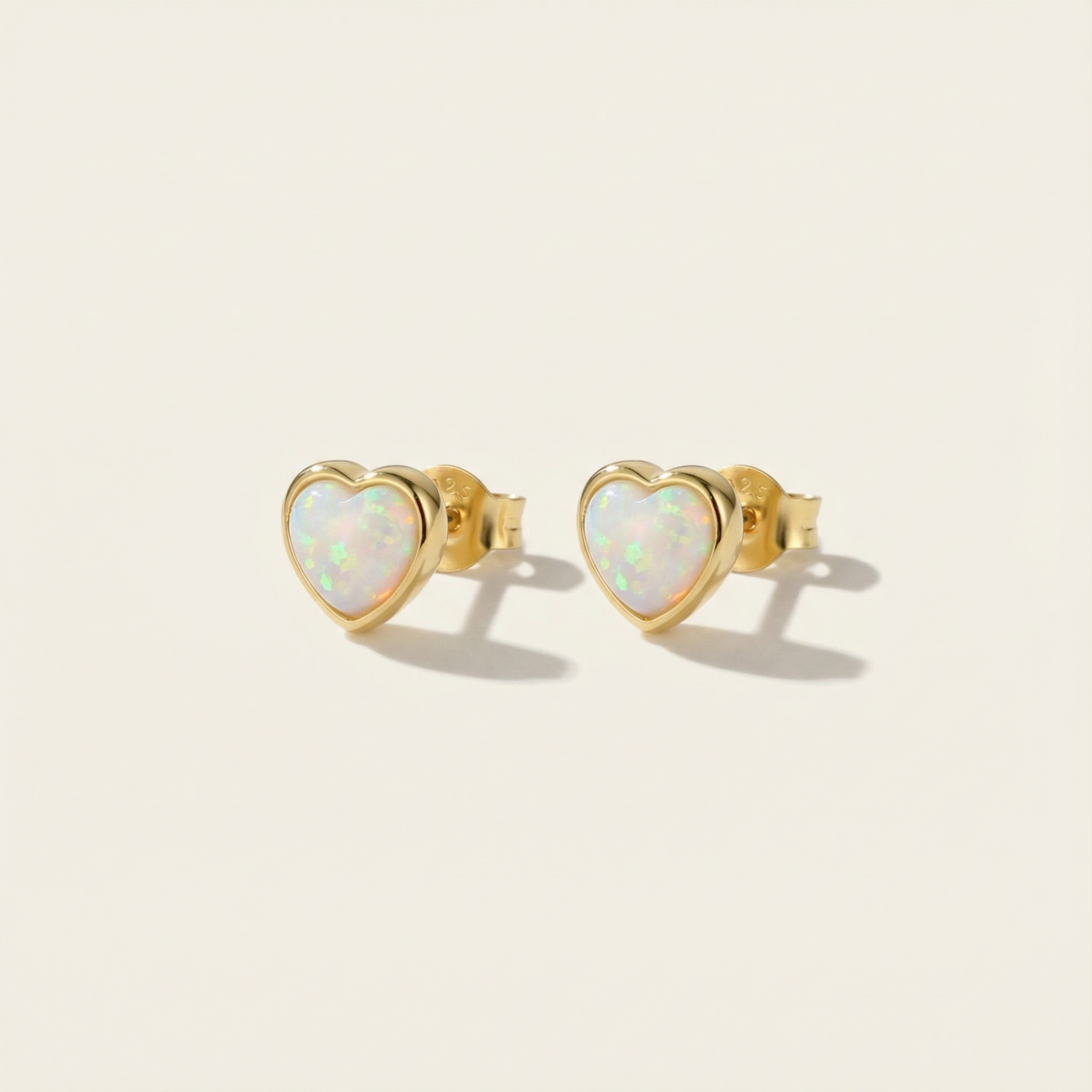 Heart-shaped opal earrings with gold frames on a beige background