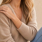 Person wearing a beige sweater and gold tarnish free bracelet with a neutral background