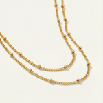 Gold satellite necklace on a light gray background