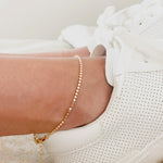 a women wearing a gold ankle bracelet