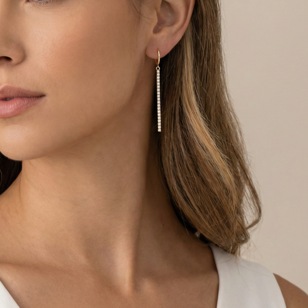 Close-up of a woman wearing a gold earring with a beige background