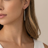 Close-up of a woman wearing a gold earring with a beige background