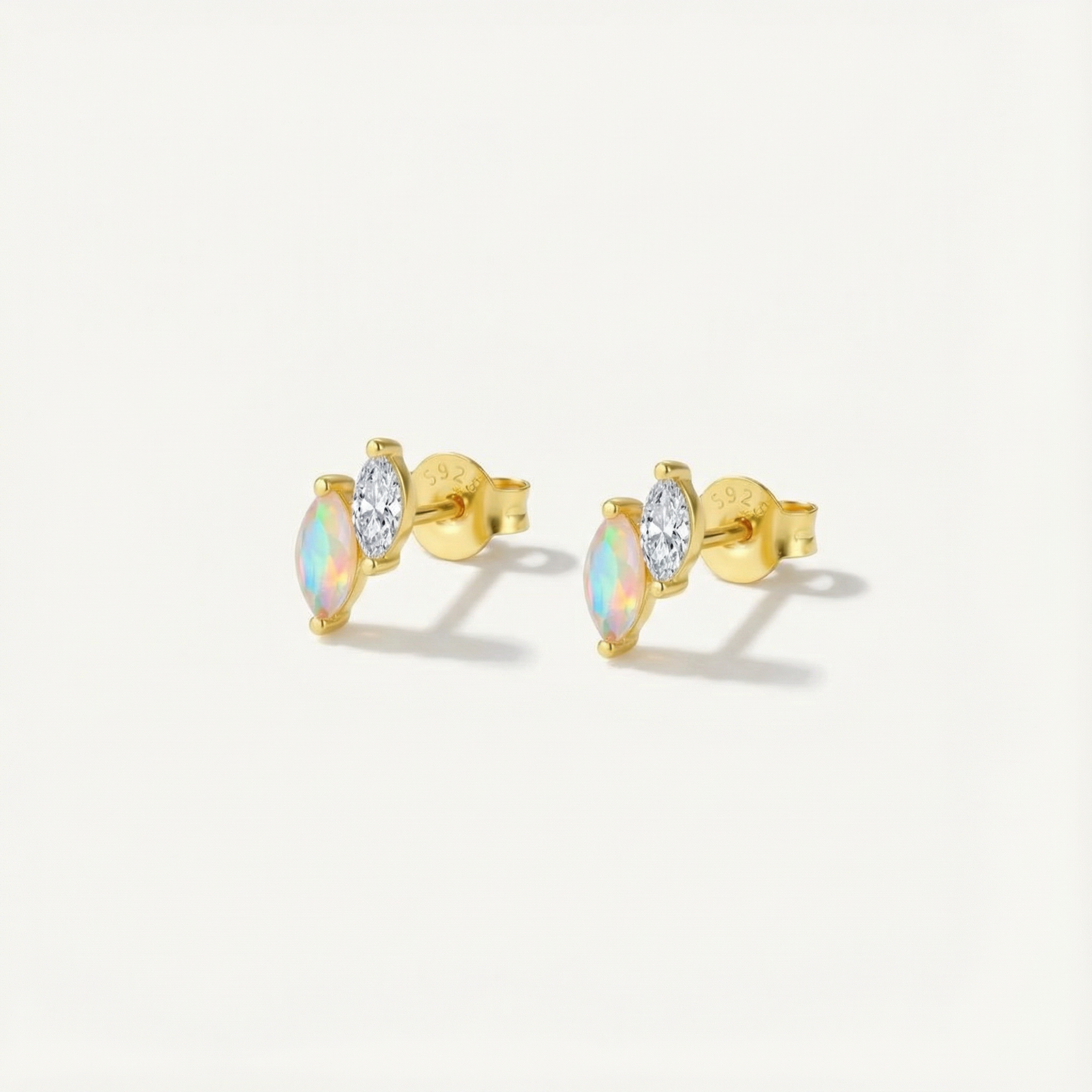 Gold earrings with opal and diamond stones on a light gray background