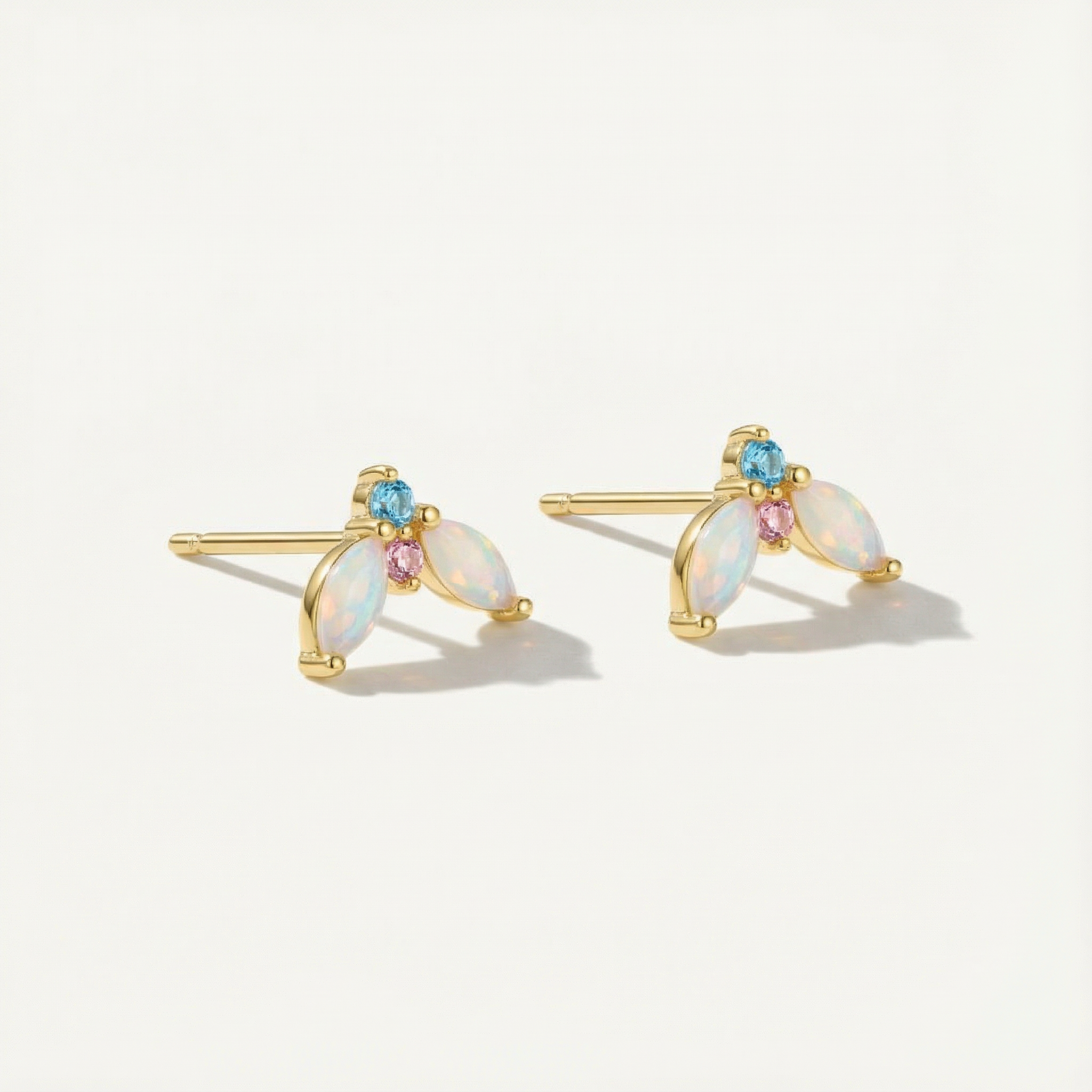 Pair of gold earrings with opal gemstones on a white background