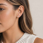 Close-up of a woman wearing an opal stud earrings with a neutral background