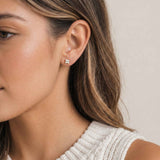 Close-up of a woman wearing an opal stud earrings with a neutral background